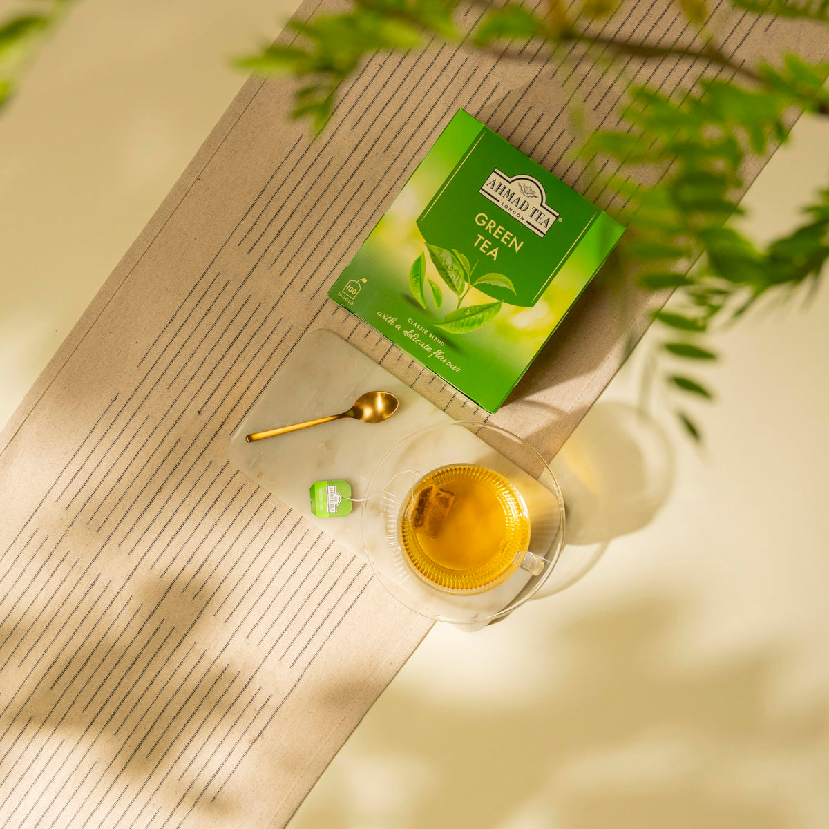 Steaming cup of green tea with Ahmad Tea box