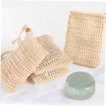 Four multi colored mesh soap bags hanging to dry in a modern bathroom setup.