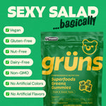 A single serving of Grüns multivitamin gummies held in a hand to demonstrate size and appetizing strawberry green texture.