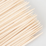 Multifunctional wooden skewers being used at a festive dinner table setting for dental care and finger food.
