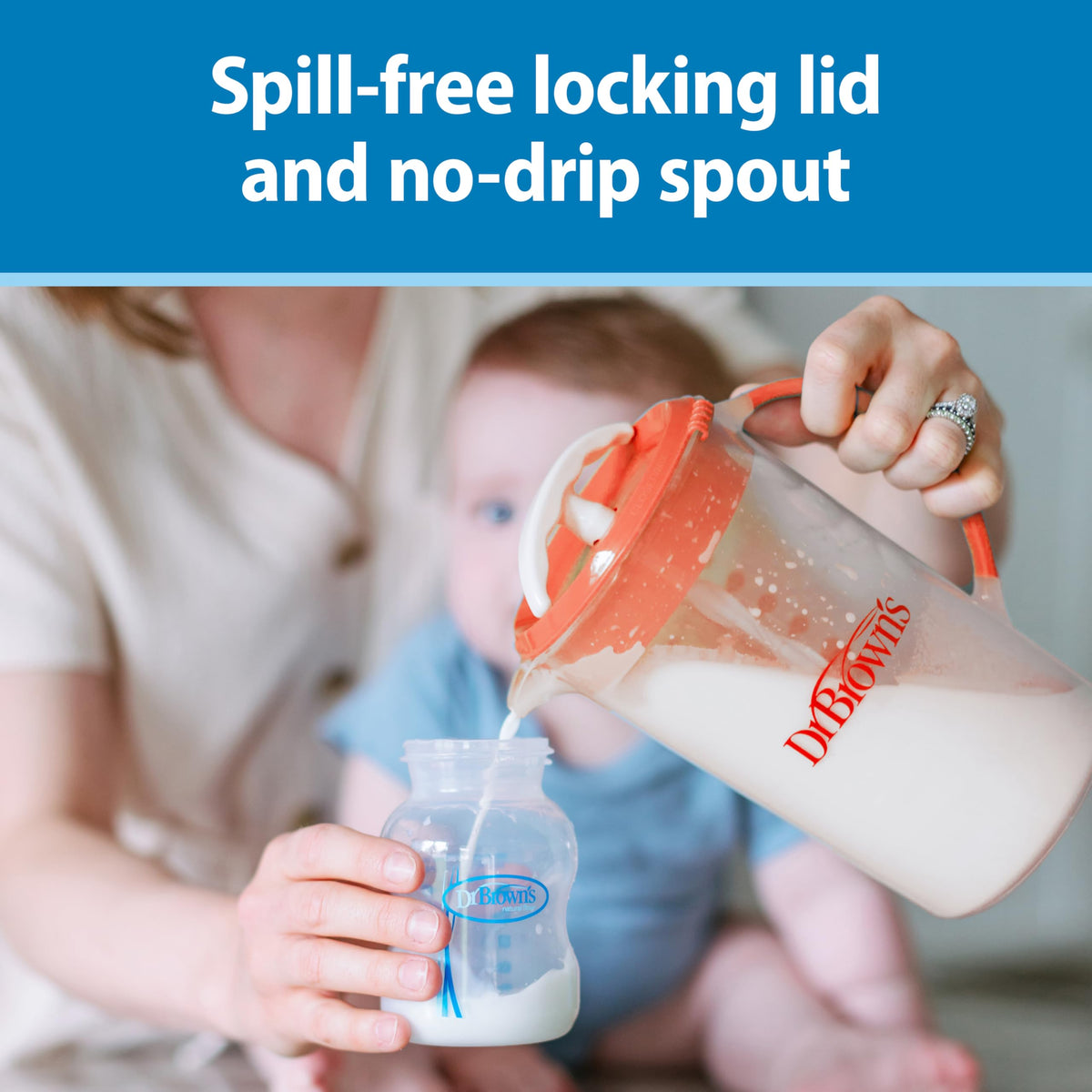 A parent pouring smooth clump-free baby formula from the blue Dr. Brown's pitcher into a standard infant feeding bottle.