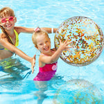 Six pieces of Civaner gold confetti pool balloons spread out on a sandy beach.