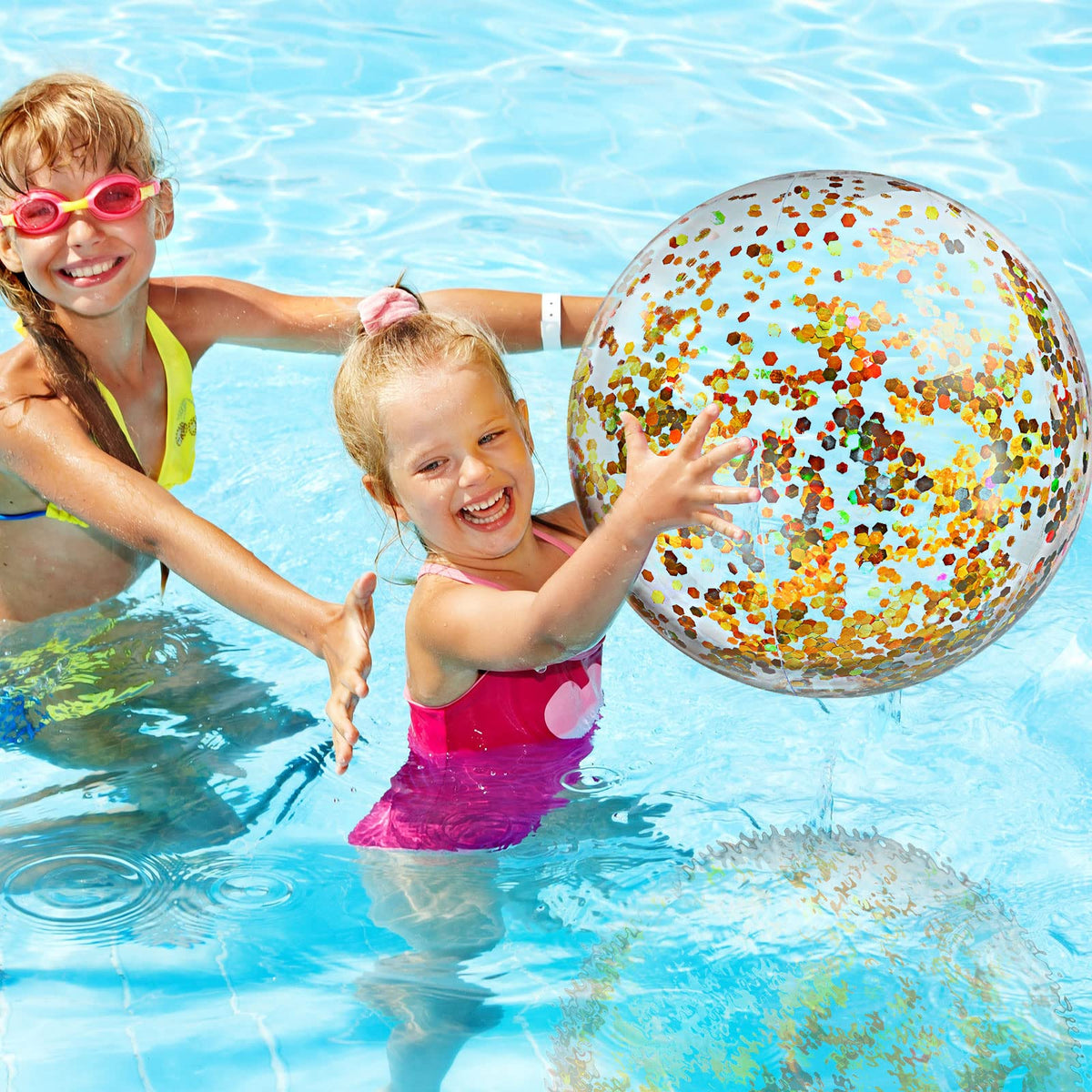 Six pieces of Civaner gold confetti pool balloons spread out on a sandy beach.