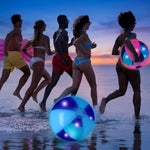 Adults playing with giant neon inflatable balls at an outdoor evening music festival.
