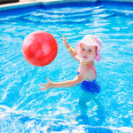 A child bouncing the blue and red marble pattern rubber kickball on a backyard concrete path.