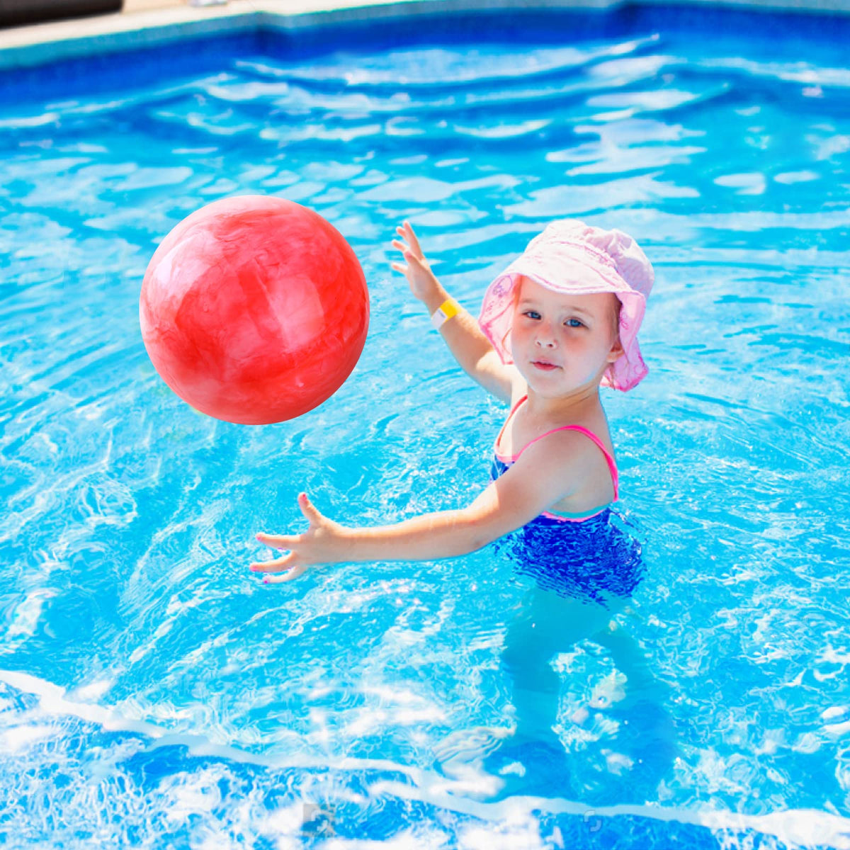 A child bouncing the blue and red marble pattern rubber kickball on a backyard concrete path.