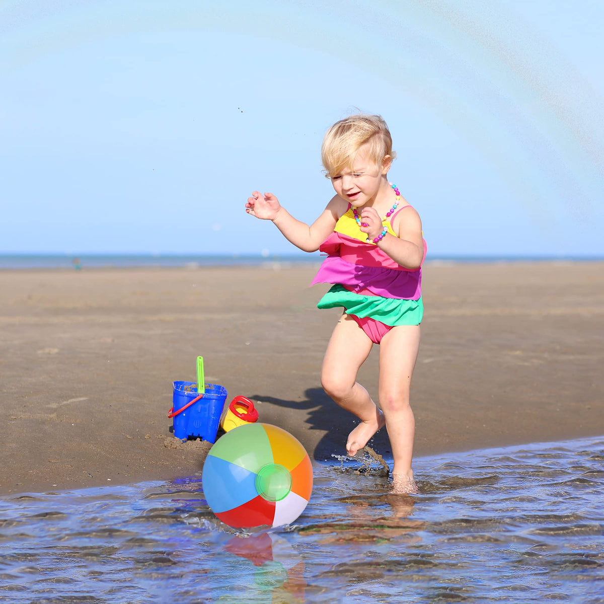 Kids playing with colorful twelve inch blow up water toys at an outdoor birthday celebration.