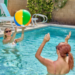 Four inflated large twenty inch rainbow water balls floating on clean blue swimming pool water during summer time.
