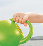 Toddler holding Hape green watering can for gardening