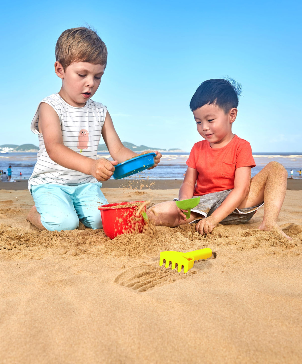Toddler playing with Hape beach bucket and shovel set