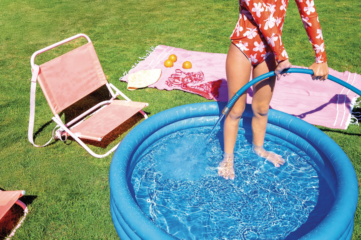 Portable three ring circular water splash pool for children inflated on an outdoor concrete patio surface.