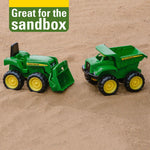 Toddler playing with John Deere tractor and dump truck in sand