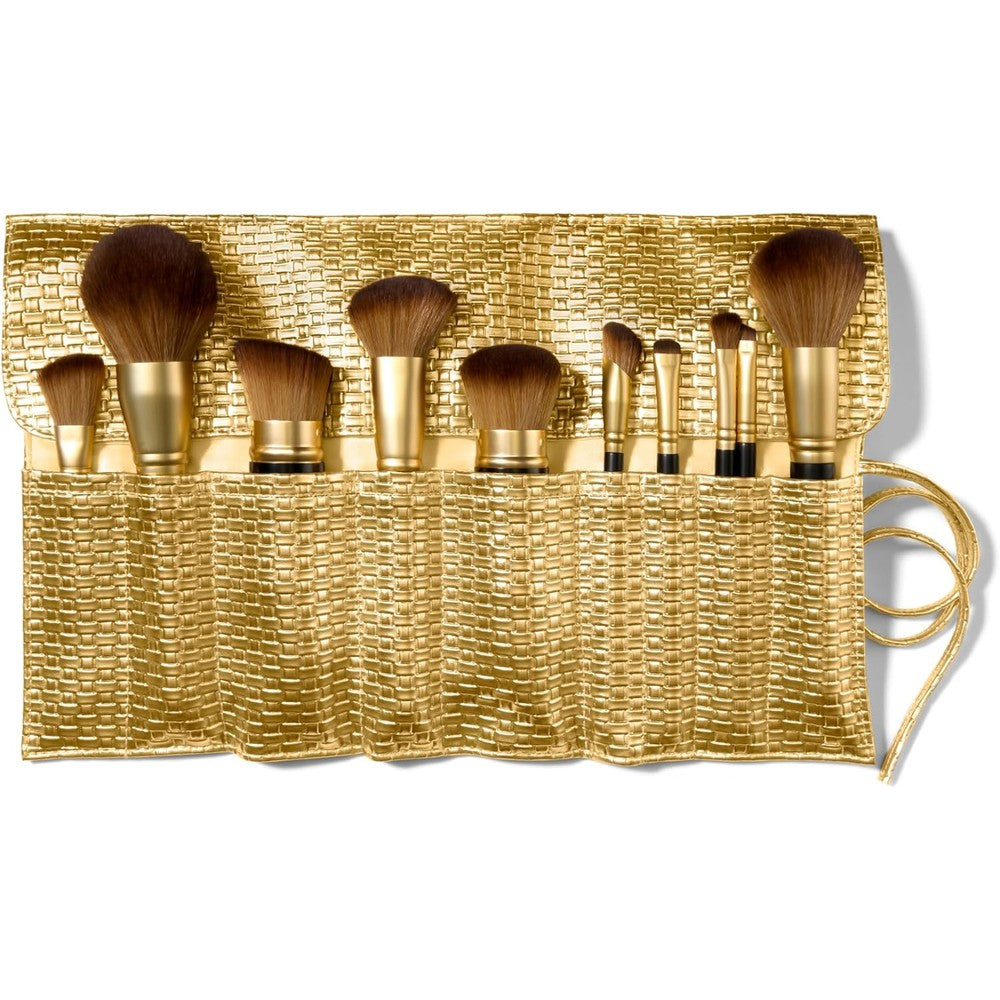 Laura Geller New York The Brush Vault front view showing ten makeup brushes with gold handles arranged next to a woven gold travel bag