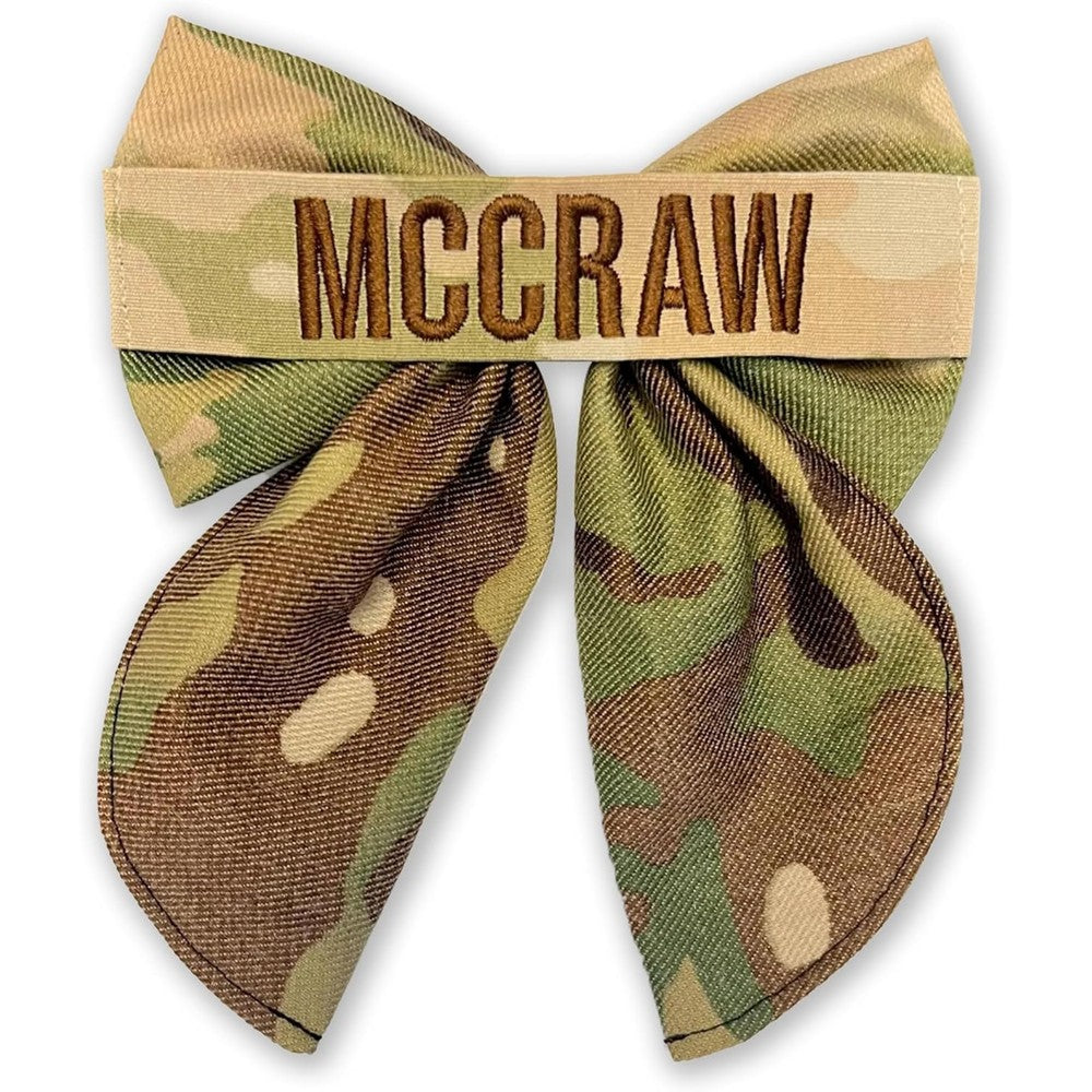 CureHug personalized army hair bow front view displaying custom embroidered nametape on camouflage fabric