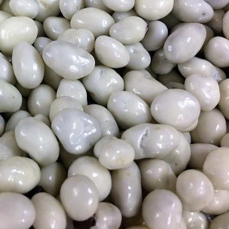 A close-up pile of smooth, glossy white to off-white pebble-shaped decorative stones or river rocks.