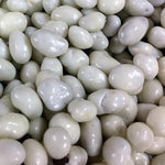 A close-up pile of smooth, glossy white to off-white pebble-shaped decorative stones or river rocks.